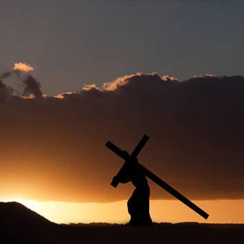 The figure of Jesus Christ carrying the cross up Calvary on Good Friday. The sky is dark and ominus.