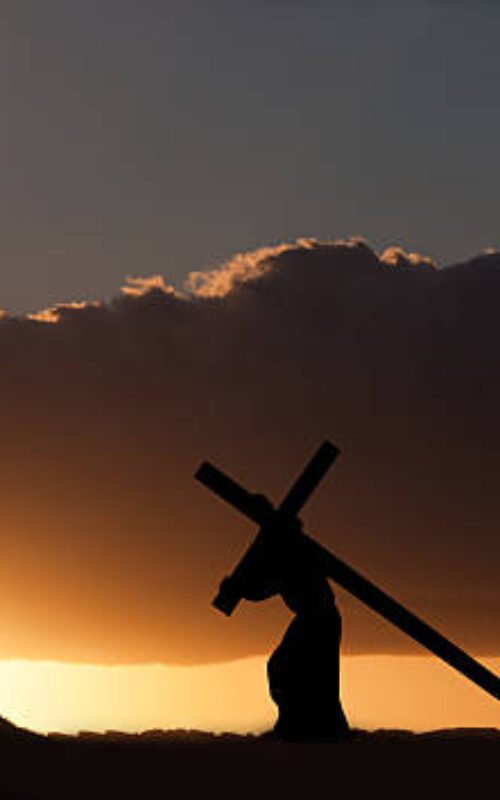 The figure of Jesus Christ carrying the cross up Calvary on Good Friday. The sky is dark and ominus.